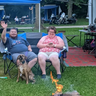 man and woman sitting at campfire