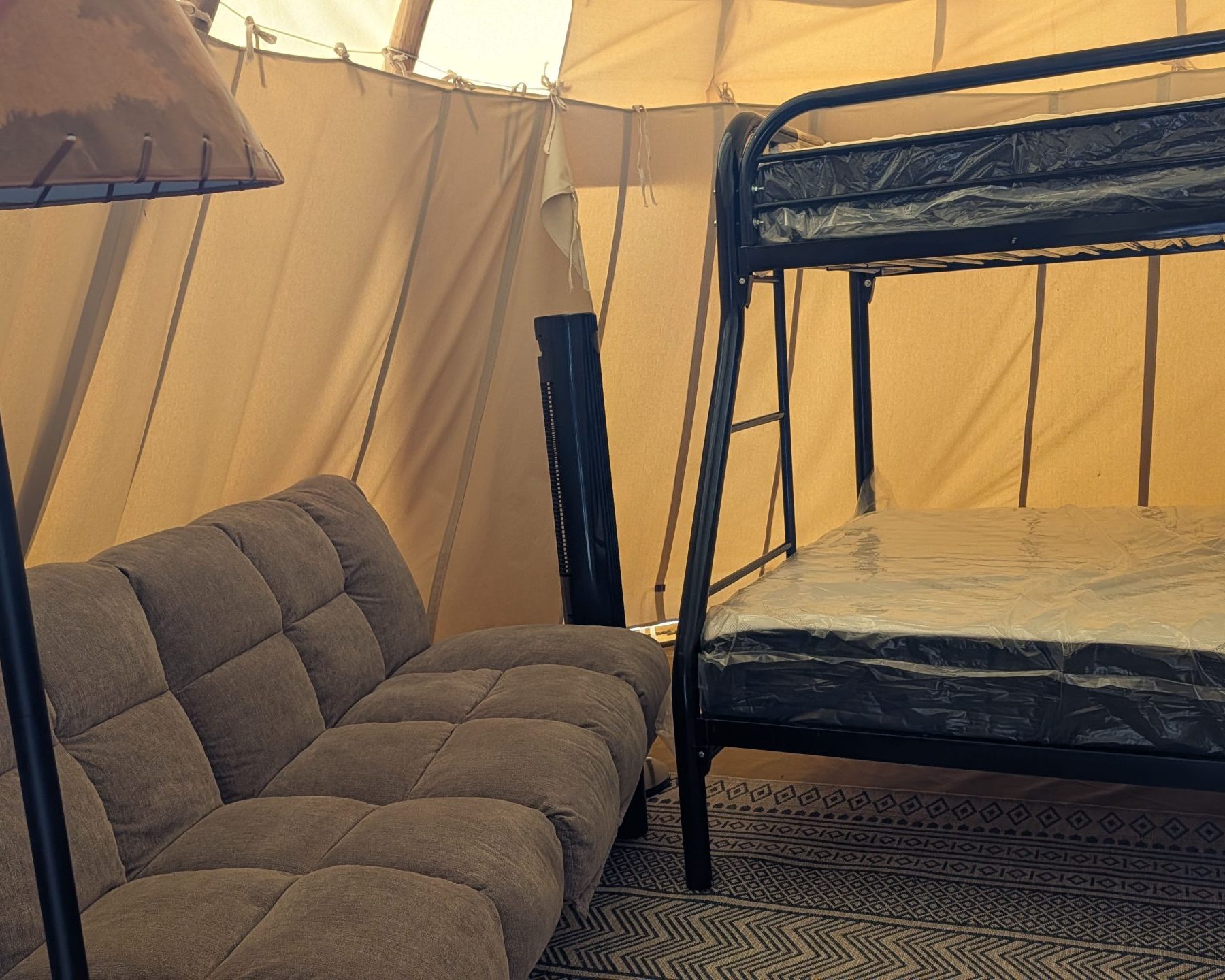 Tipi interior with bunk bed and refrigerator at Crystal Rock Campground